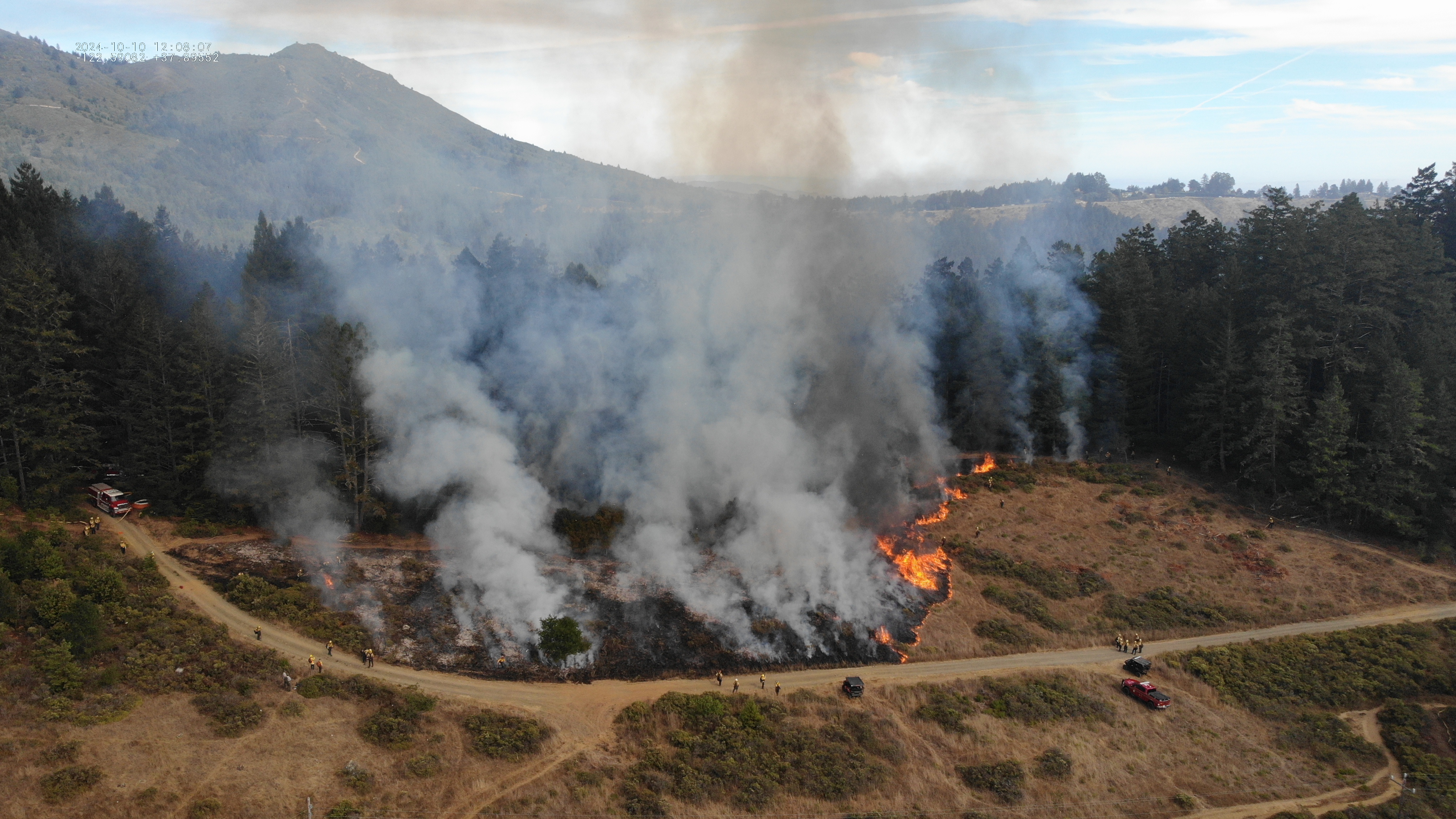 Aerial photo of burning grassland with firefighters observing taken Aerial photo of burning grassland with firefighters observing taken